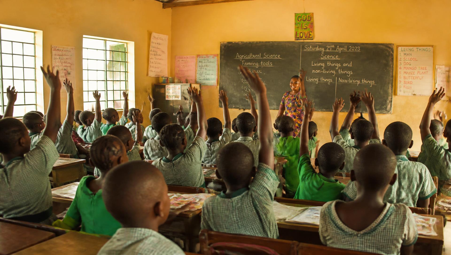 Schoolchildren raising their hands in a classroom